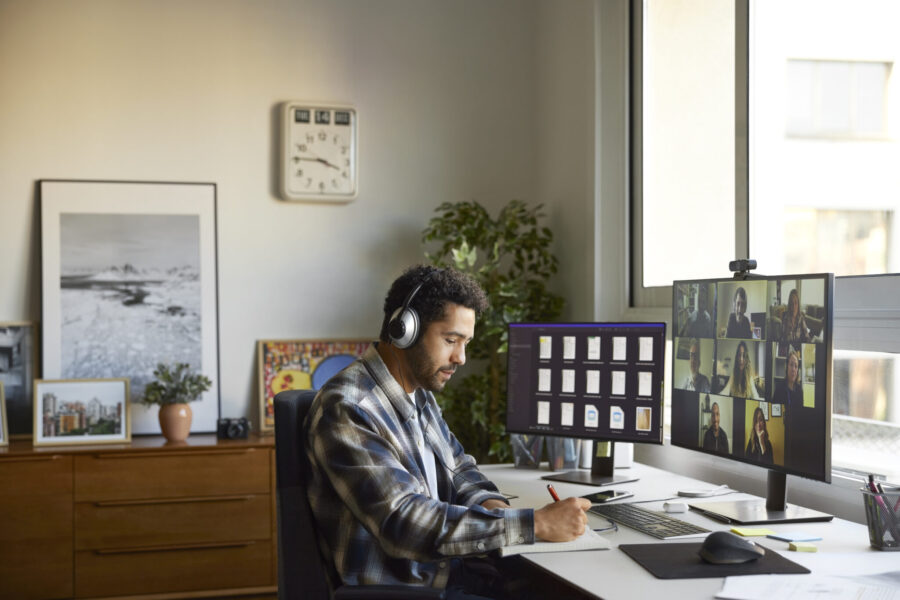 Businessman writing in diary while discussing during video conference. Multiracial male and female colleagues attending online meeting. They are planning business strategy.