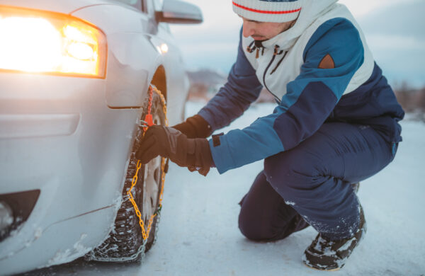 Adult Man Tightening Tire Chains on His Car