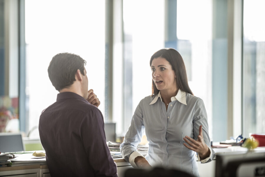 Female business manager talking to male employee in modern office. Caucasian businesswoman in discussion with colleague.