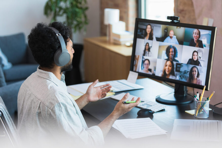 Video conferencing from home, the unrecognizable mid adult man leads a staff meeting with diverse employees.