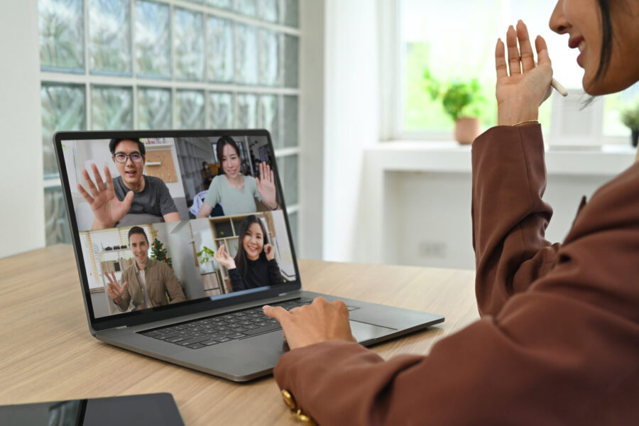 Smiling young female employee having video call with diverse colleagues on online briefing with laptop computer.