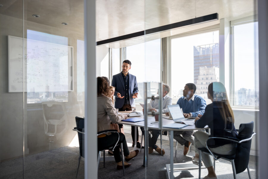 Successful Latin American business man talking to a group of people in a meeting a the office