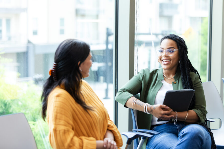 The young adult female counselor smiles when the unrecognizable woman shares her good news.