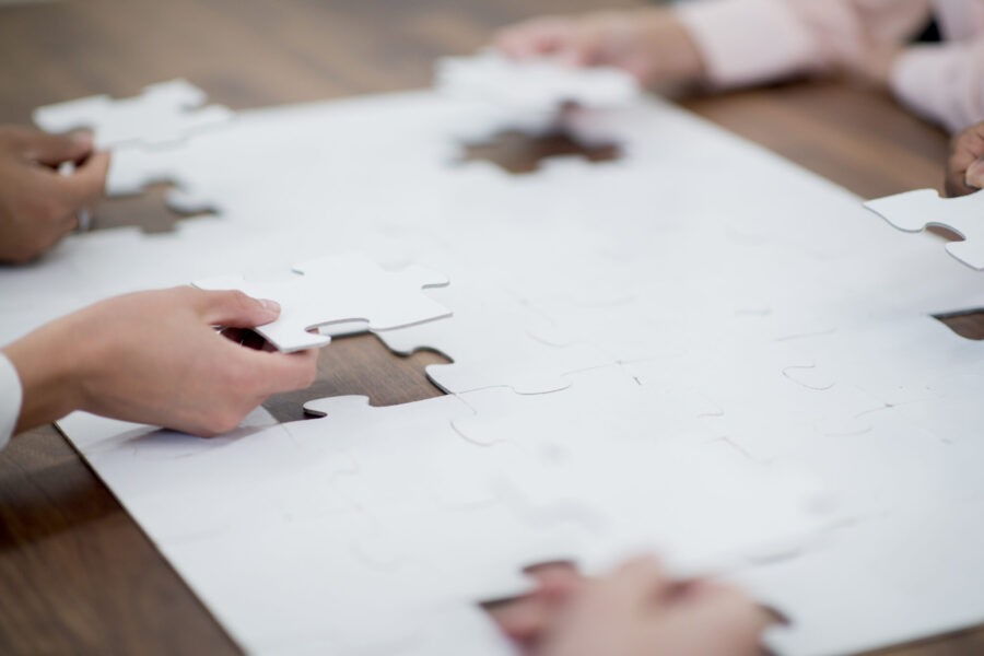 A multi-ethnic group of business associates are putting the pieces of a puzzle together and are working on team building and problem solving.