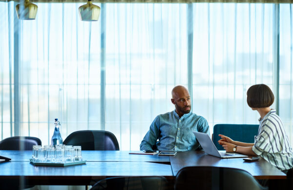 Two businesspeople having a meeting at a table in a large conference room