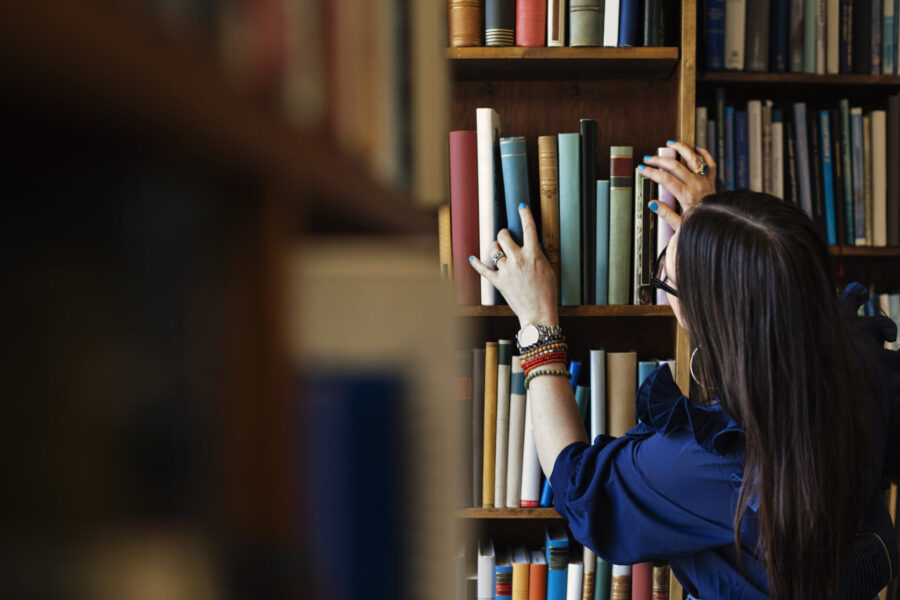 Rear View Of Woman Searching Book In Library