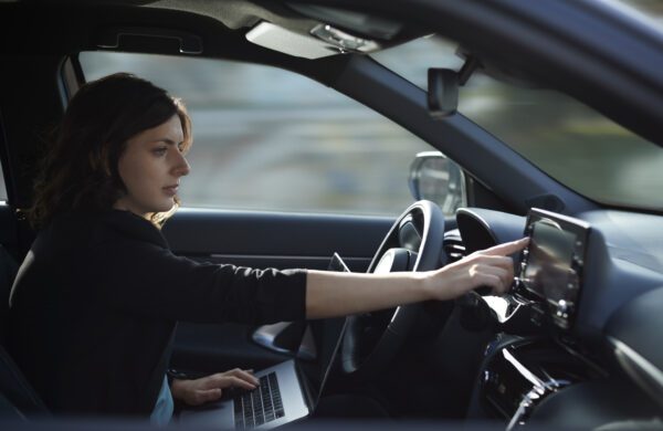 Businesswoman with laptop using navigation device in driverless car