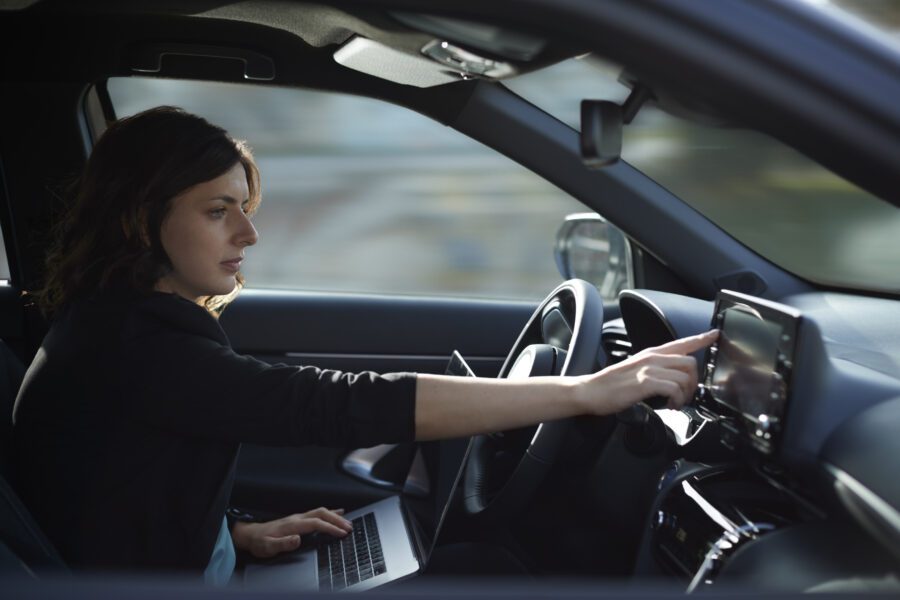 Businesswoman with laptop using navigation device in driverless car