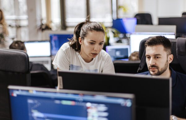 Young Caucasian male and female computer programmers working together on a computer at the open space office