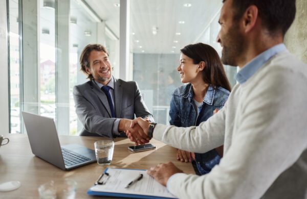 Happy insurance agent came to a successful agreement with a couple on a meeting in the office.