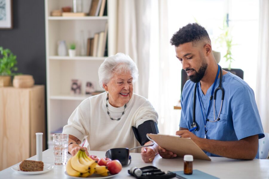 Healthcare Worker Or Caregiver Visiting Senior Woman Indoors At Home, Measuring Blood Pressure.