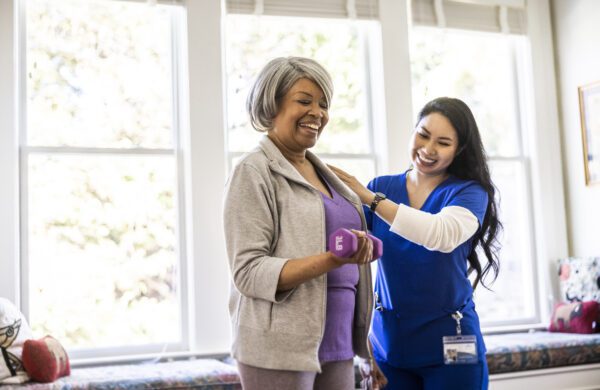 At home nurse helping senior woman with physical therapy at home