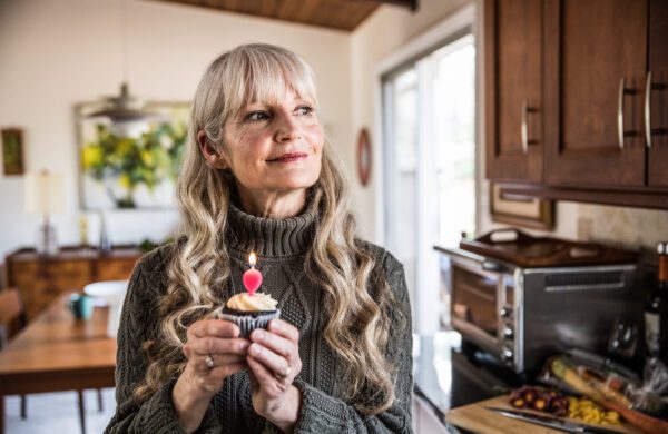 Senior woman holding a cupcake while celebrating her birthday
