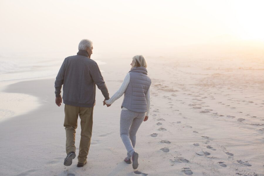 Senior Couple Walking On A Beach Together