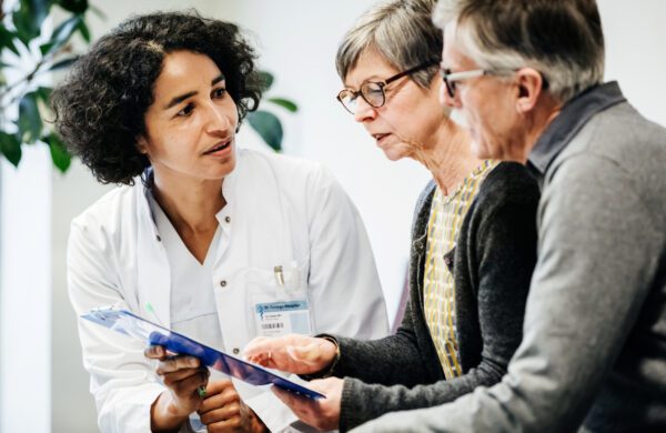 Doctor discussing senior couple's medical information while providing guidance and support