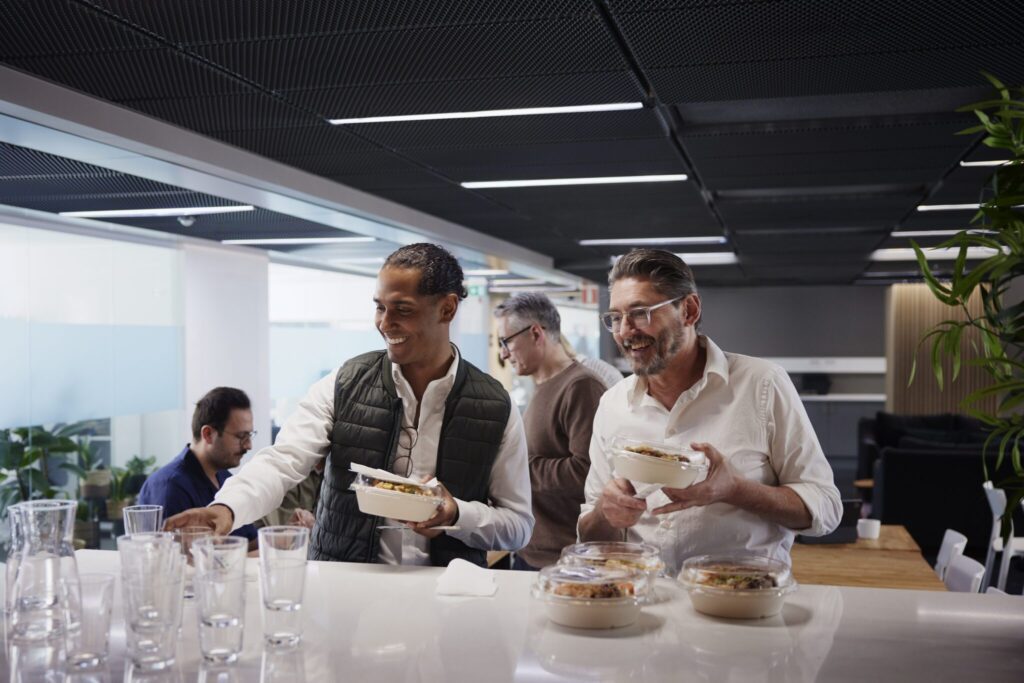 Group of business people socializing during a catered team lunch in the office breakroom
