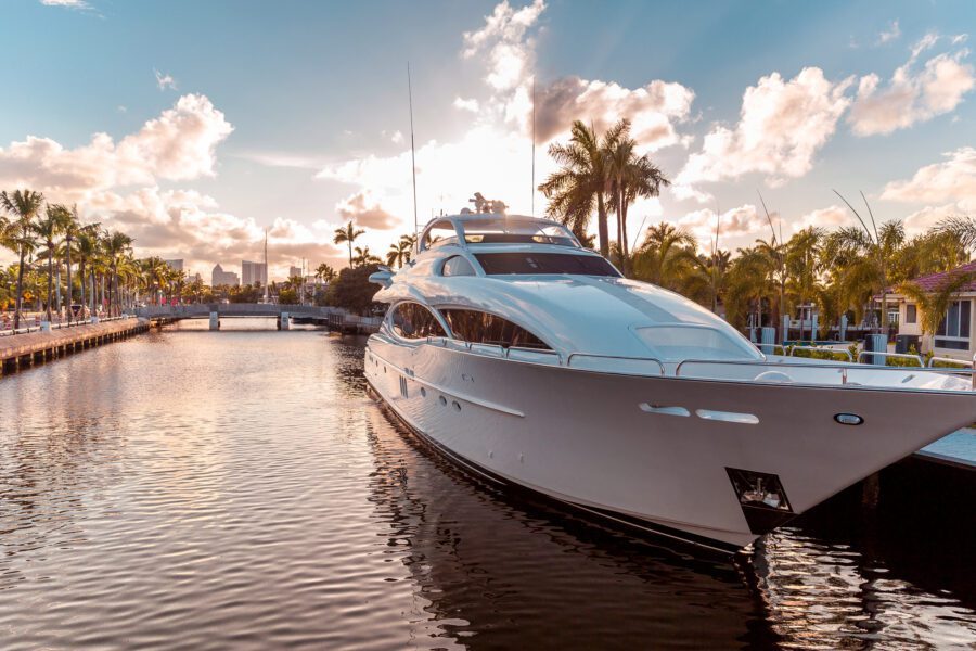 Yacht docked in harbor with other large boats surrounded by palm trees