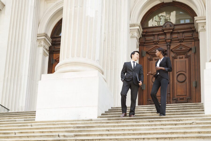 Two business professionals discussing work while walking down the steps of an office building