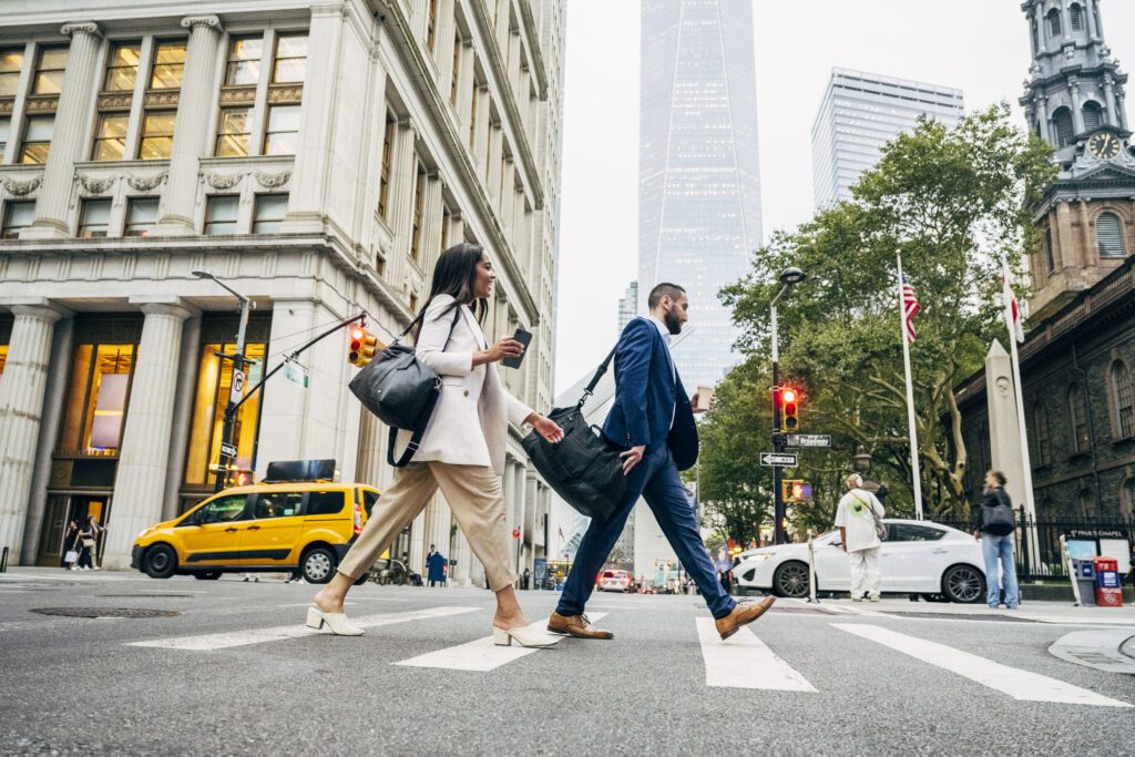 Full length side view of male and female coworkers in summer attire walking with shoulder bags after work