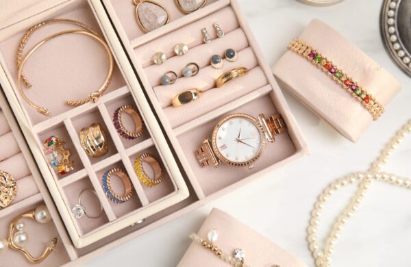 Jewelry box with valuable items in it, like gold rings, earrings and bracelet, placed on white table