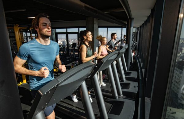 Group of determined athletic people running on treadmills in a gym in the city