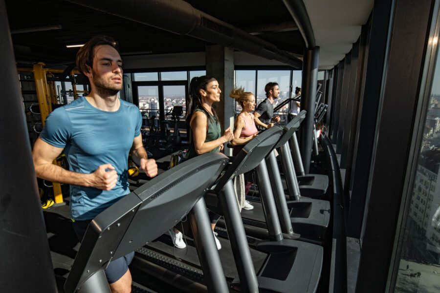 Group of determined athletic people running on treadmills in a gym in the city