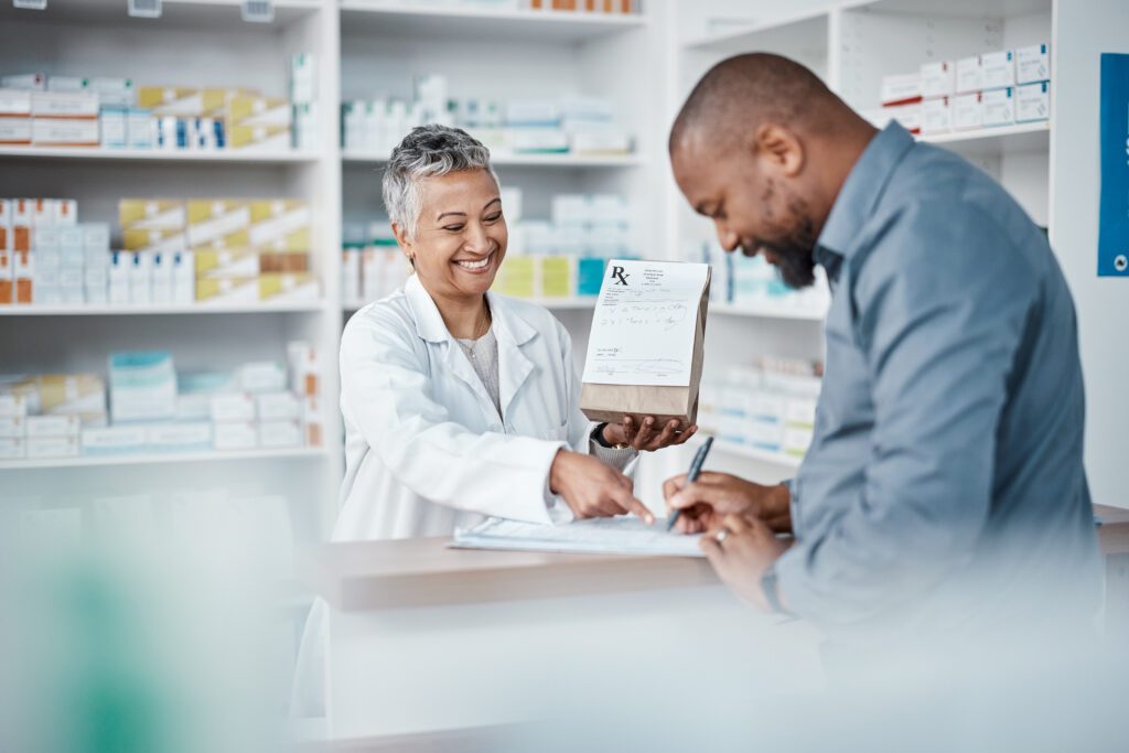 Pharmacist assisting male customer while shopping for medicine in pharmacy and writing medical information for prescription