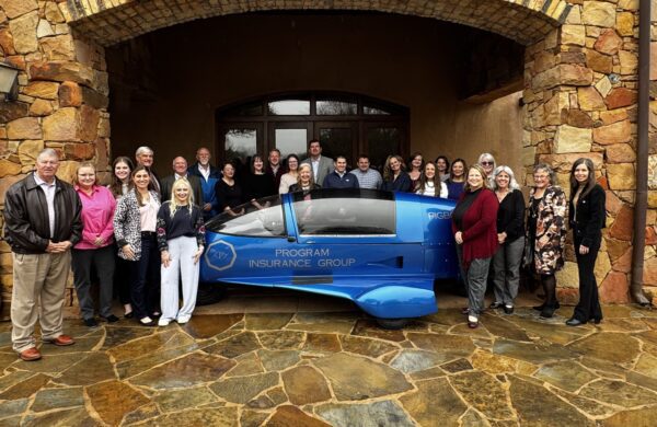 The Program Insurance Group team stands near a sponsored vehicle