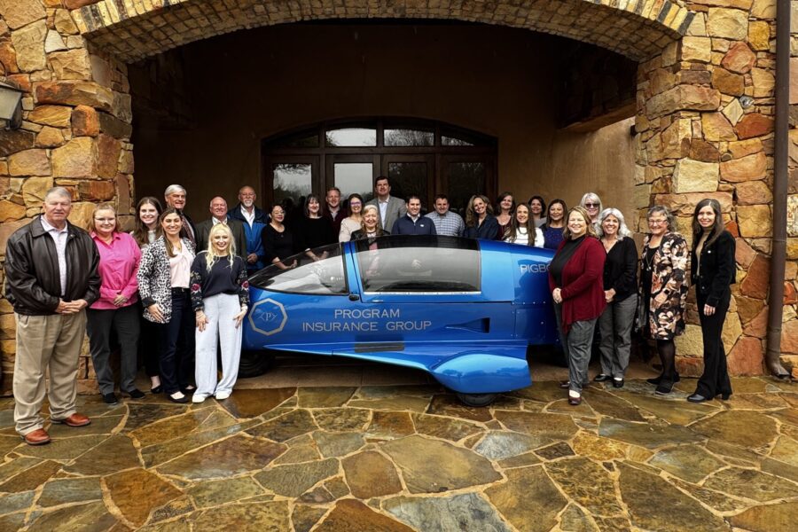 The Program Insurance Group team stands near a sponsored vehicle