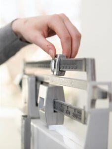 A hand carefully adjusts the weight on a mechanical balance scale.