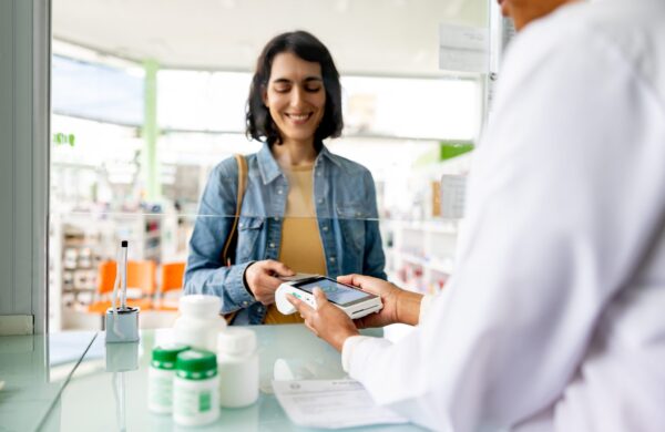 Happy woman paying by health savings benefit card while buying medicine at the pharmacy
