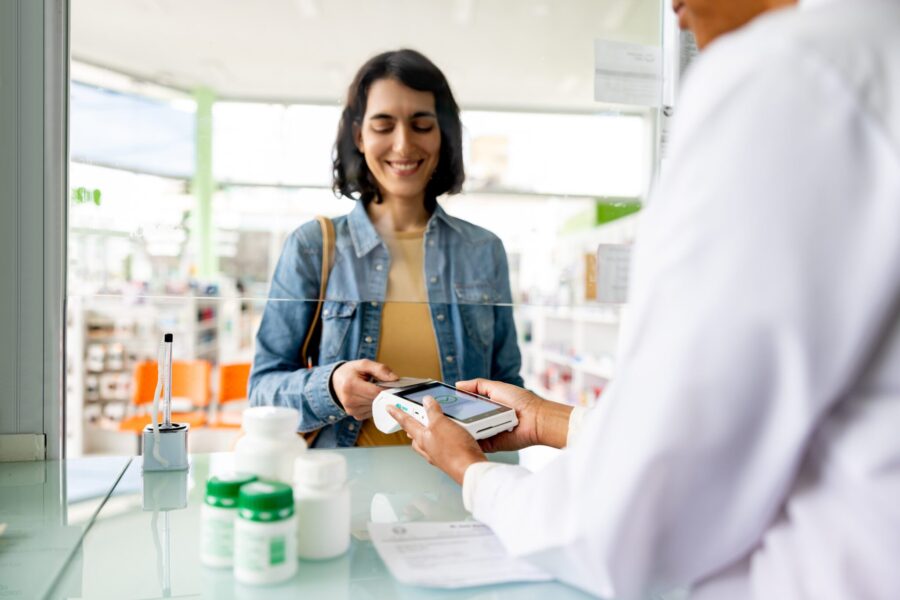 Happy woman paying by health savings benefit card while buying medicine at the pharmacy