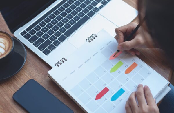 Business woman checking planner and taking notes on a calendar on office table
