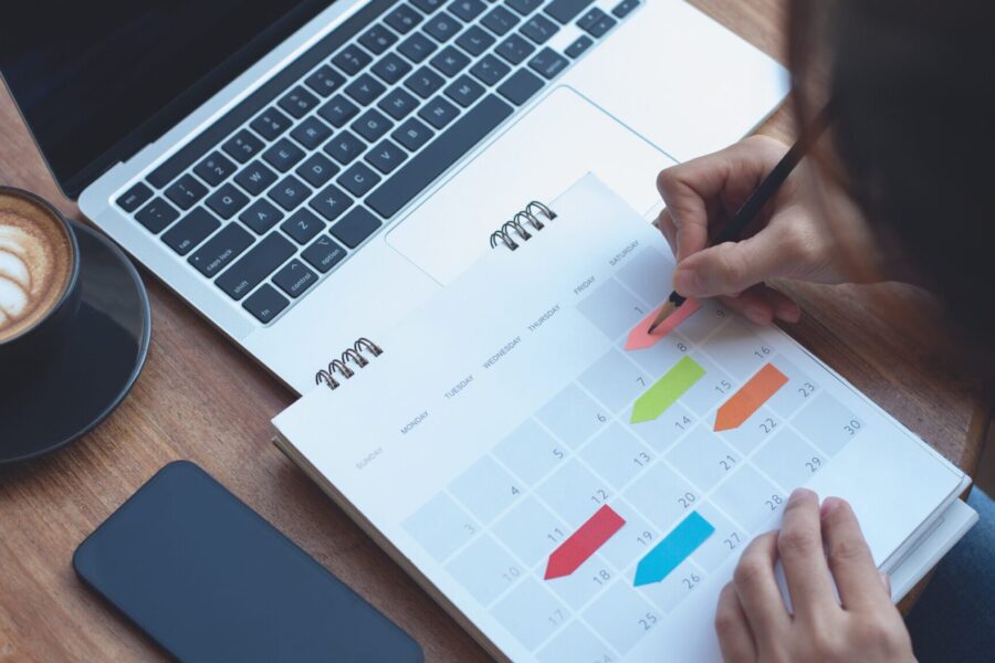 Business woman checking planner and taking notes on a calendar on office table