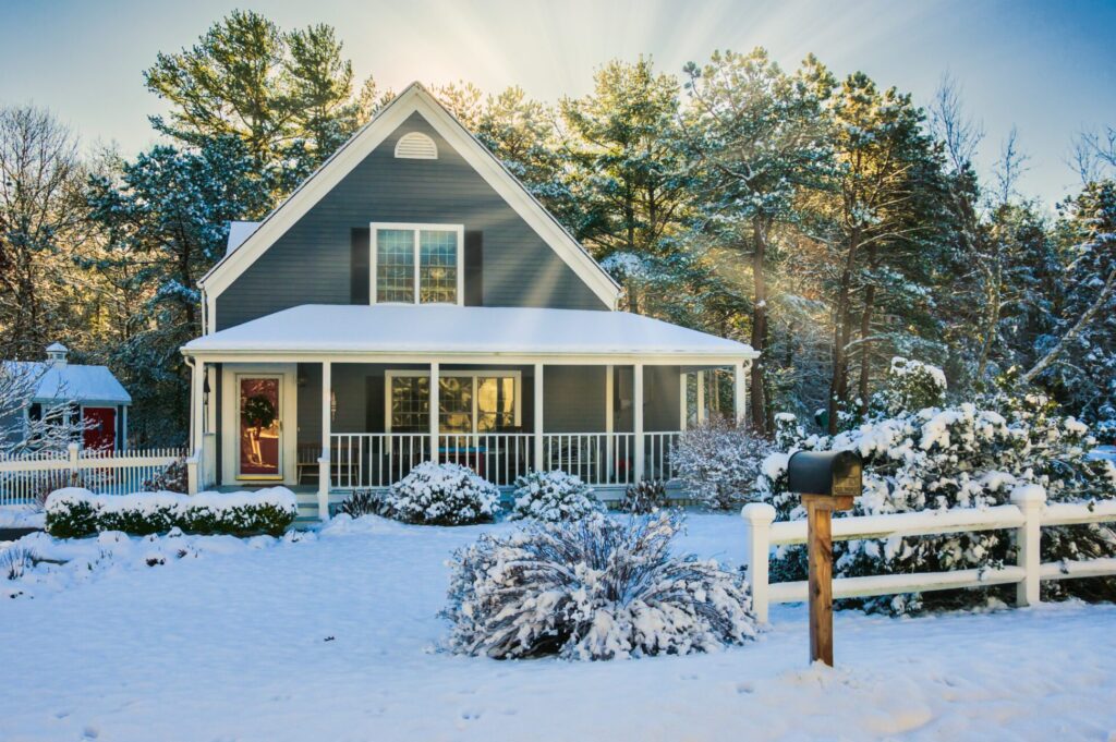 Morning sun rises and illuminates trees behind a single family home on decorated for Christmas after a light snowfall
