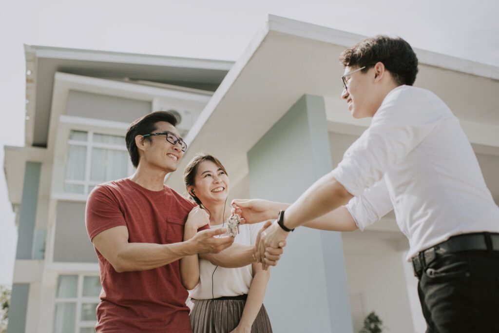 First-time homebuyers moving into new house and receiving the house keys from real estate agent