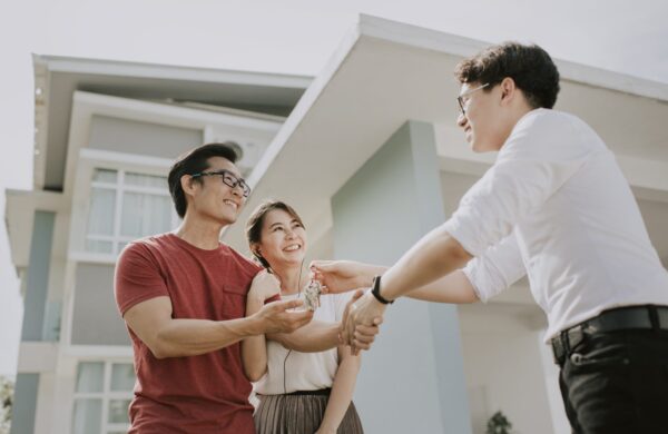 First-time homebuyers moving into new house and receiving the house keys from real estate agent