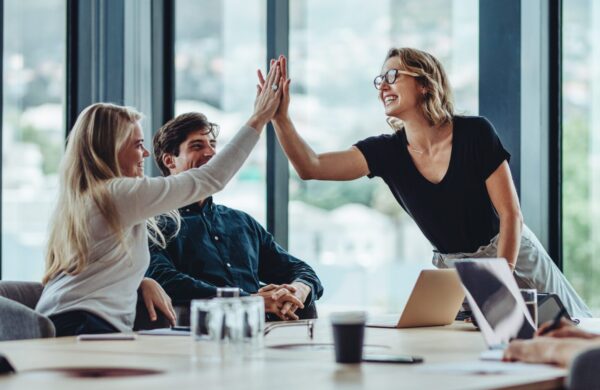 Female professional giving a high five to her colleague while celebrating in office conference room
