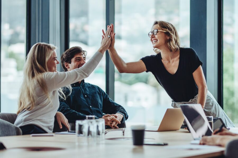 Female professional giving a high five to her colleague while celebrating in office conference room