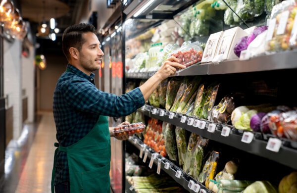 Retail clerk working at a grocery store restocking the produce aisle