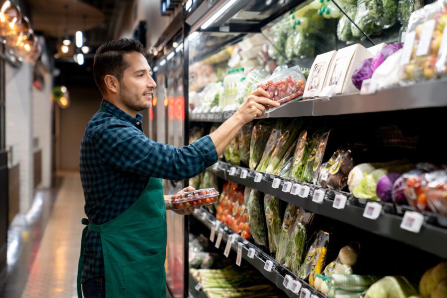 Retail clerk working at a grocery store restocking the produce aisle