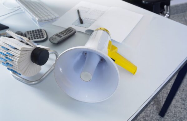 Megaphone on white desk in a modern office setting with office supplies nearby