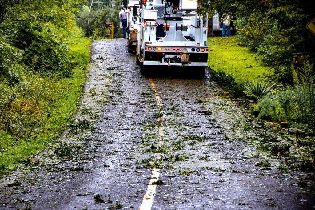 Wet road with debris after storm with power repair truck