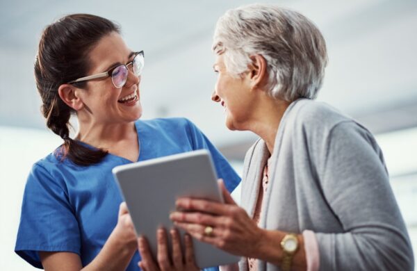 Young female nurse and her senior patient looking at a tablet in a medical setting