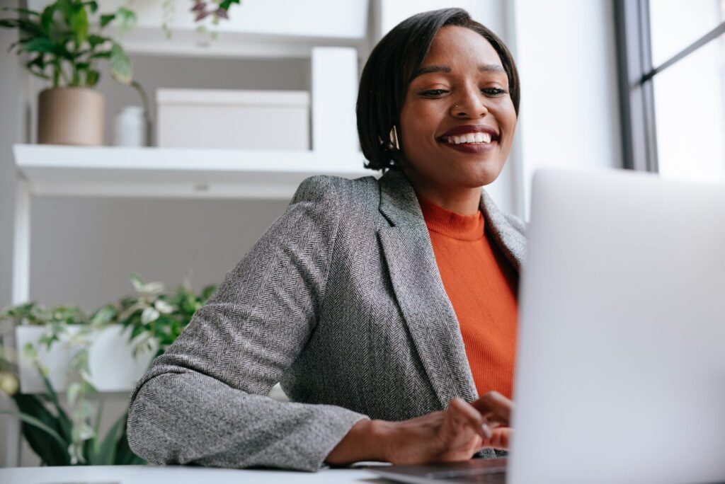 A confident professional woman works on her laptop in a modern office setting