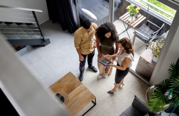 High angle view of a couple discussing details of a condo with their real estate agent while looking at a digital tablet